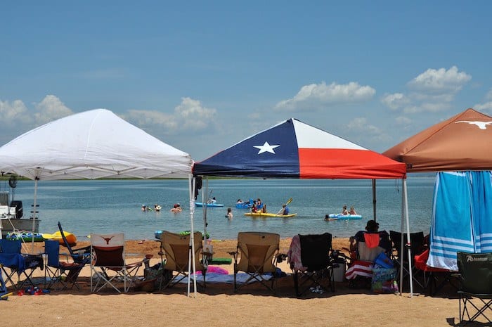 Image of guests tents set up on private sandy beach front in front of the best Hill Country lake cabin rentals in Texas. Contact Us for more information on our lake cabin rentals and the best lake house rental in Texas.