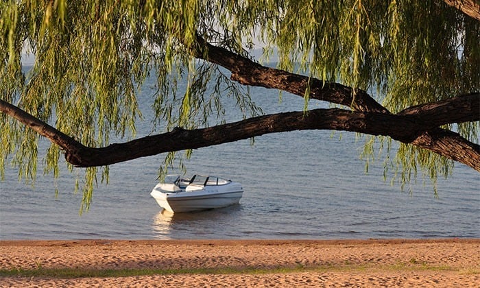 Image of a boat beneath Willow Tree on the shores of Lake Buchanan. Our cabin rentals are located steps from the lake. One of the best family-friendly trips in Texas