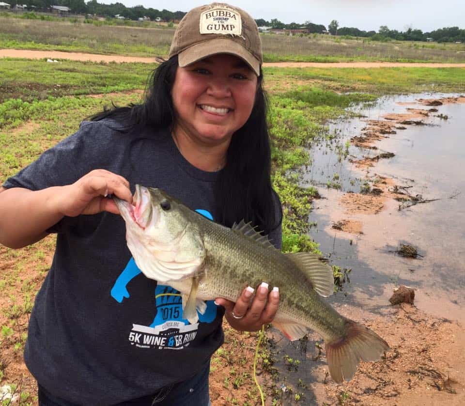 Image of a Willow Point guest catching a pretty bass of the shores of Lake Buchanan just steps from her Texas Hill Country Cabin
