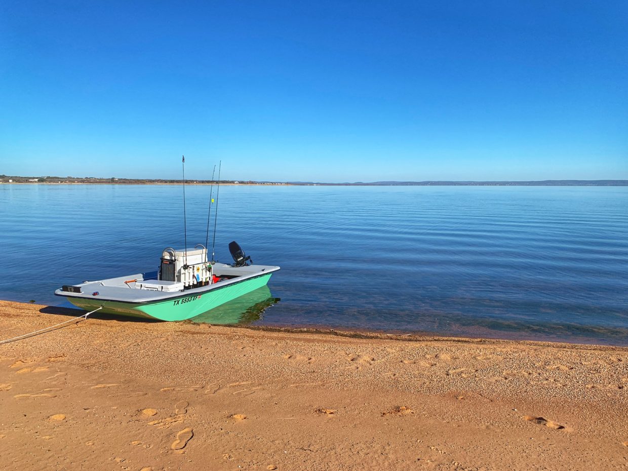 Image of a guests' boat sitting on the shores of our sandy lake beachfront.