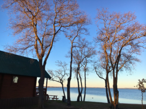 Image of side profile of lake cabin, trees, and water taken at one of the best hidden getaways in Texas - Willow Point Resort